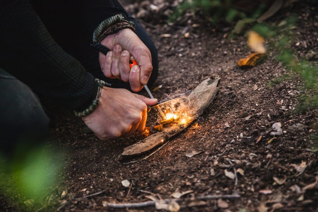 homme faisant un feu de bois à l'aide d'un allume feu en pierre